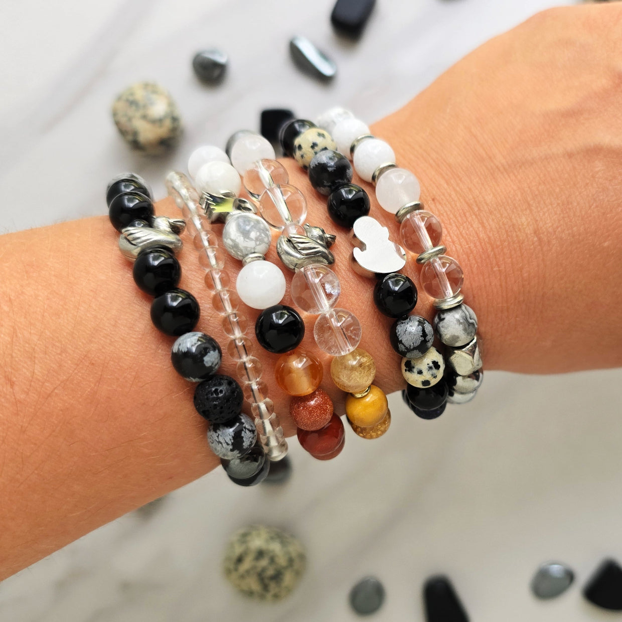 Beaded bracelet surrounded by decorative stones on a white background with 'Duck or Dare' text and brand names. Skelie duck for project fear dakota laden chelsea tanner alex