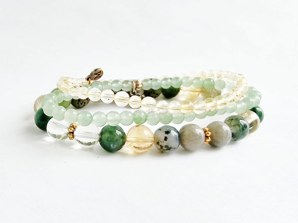 Set of beaded bracelets with green, white, and gold beads on a white background