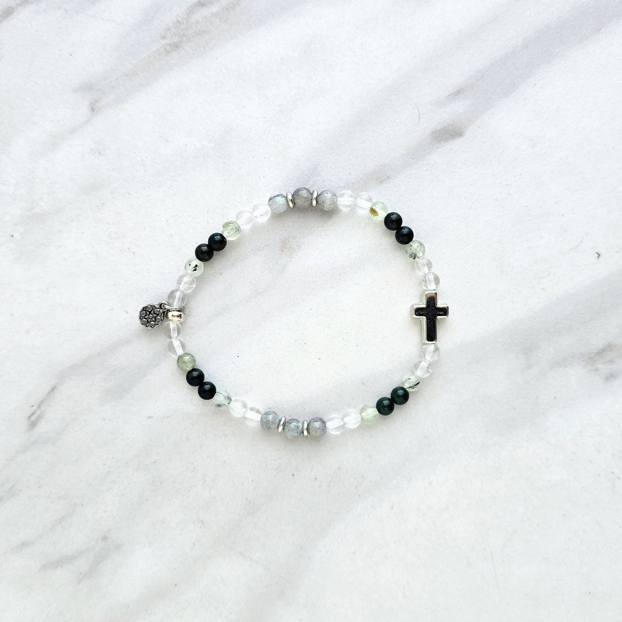 Christian Bracelet with beads and  silver colored cross on a marble background with Psalm 46:10 Be still and know