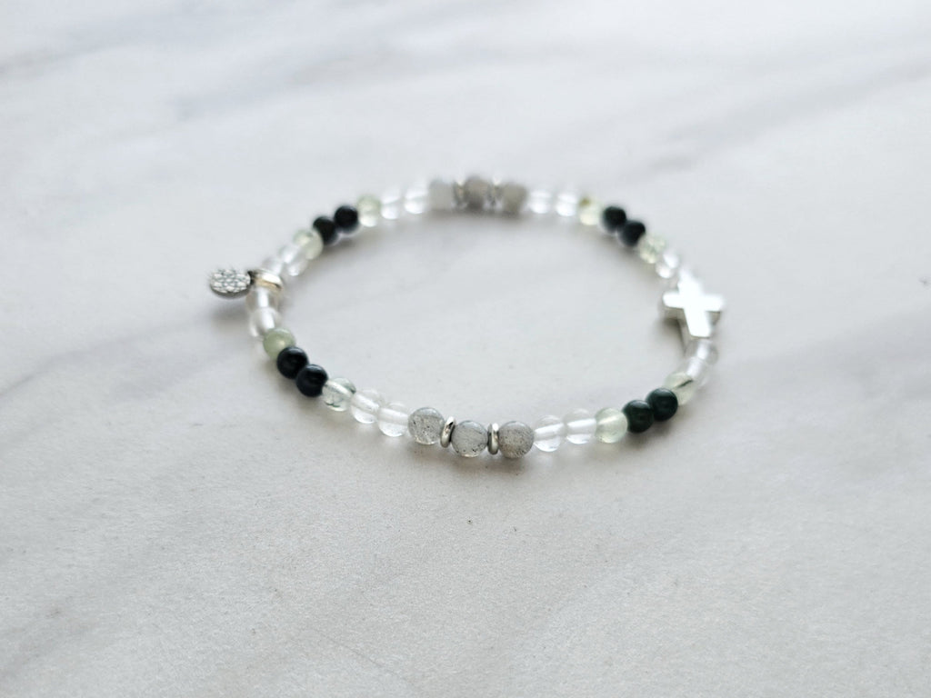 Christian Bracelet with beads and  silver colored cross on a marble background with Psalm 46:10 Be still and know