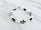 Christian Bracelet with beads and  silver colored cross on a marble background with Psalm 46:10 Be still and know