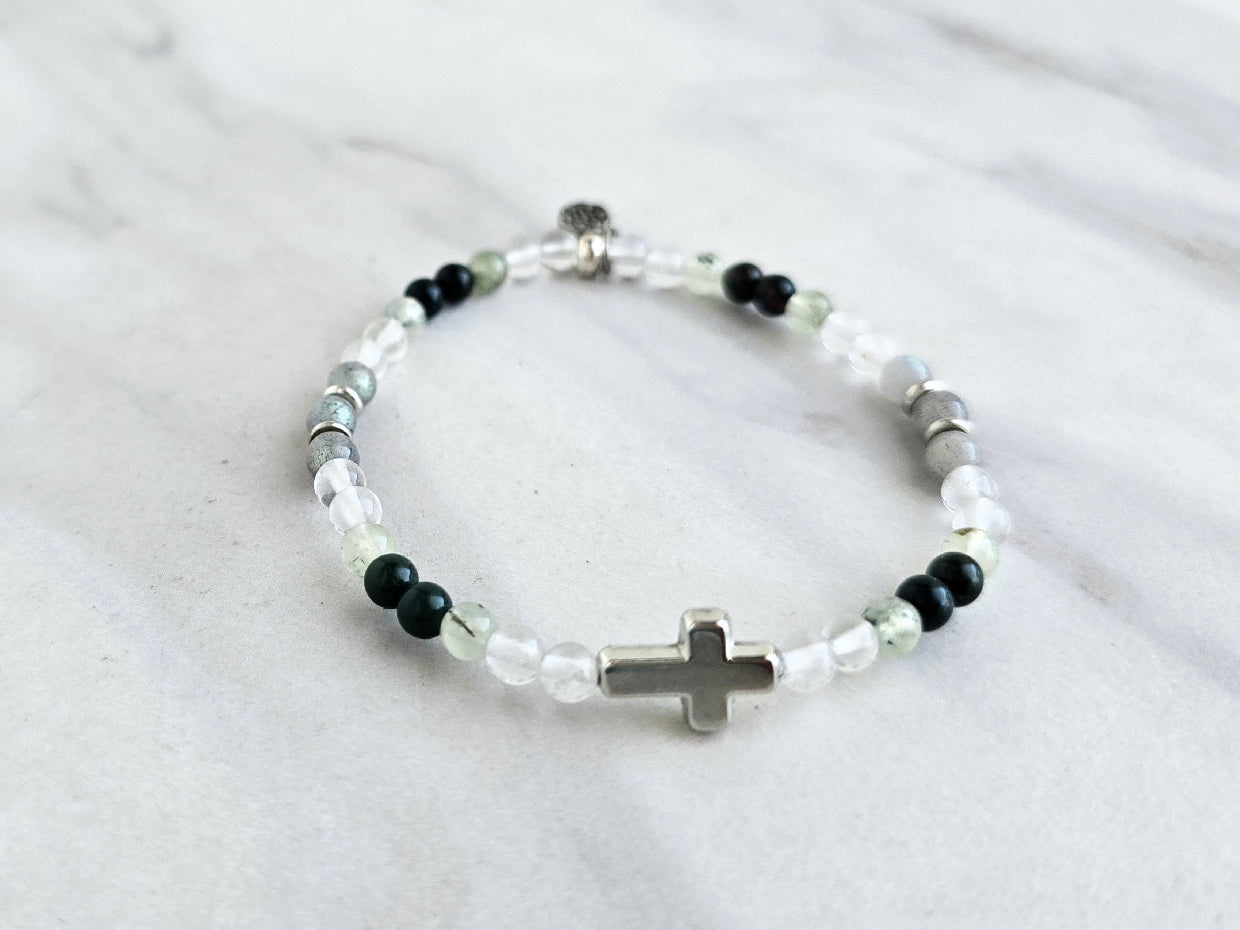 Christian Bracelet with beads and  silver colored cross on a marble background with Psalm 46:10 Be still and know