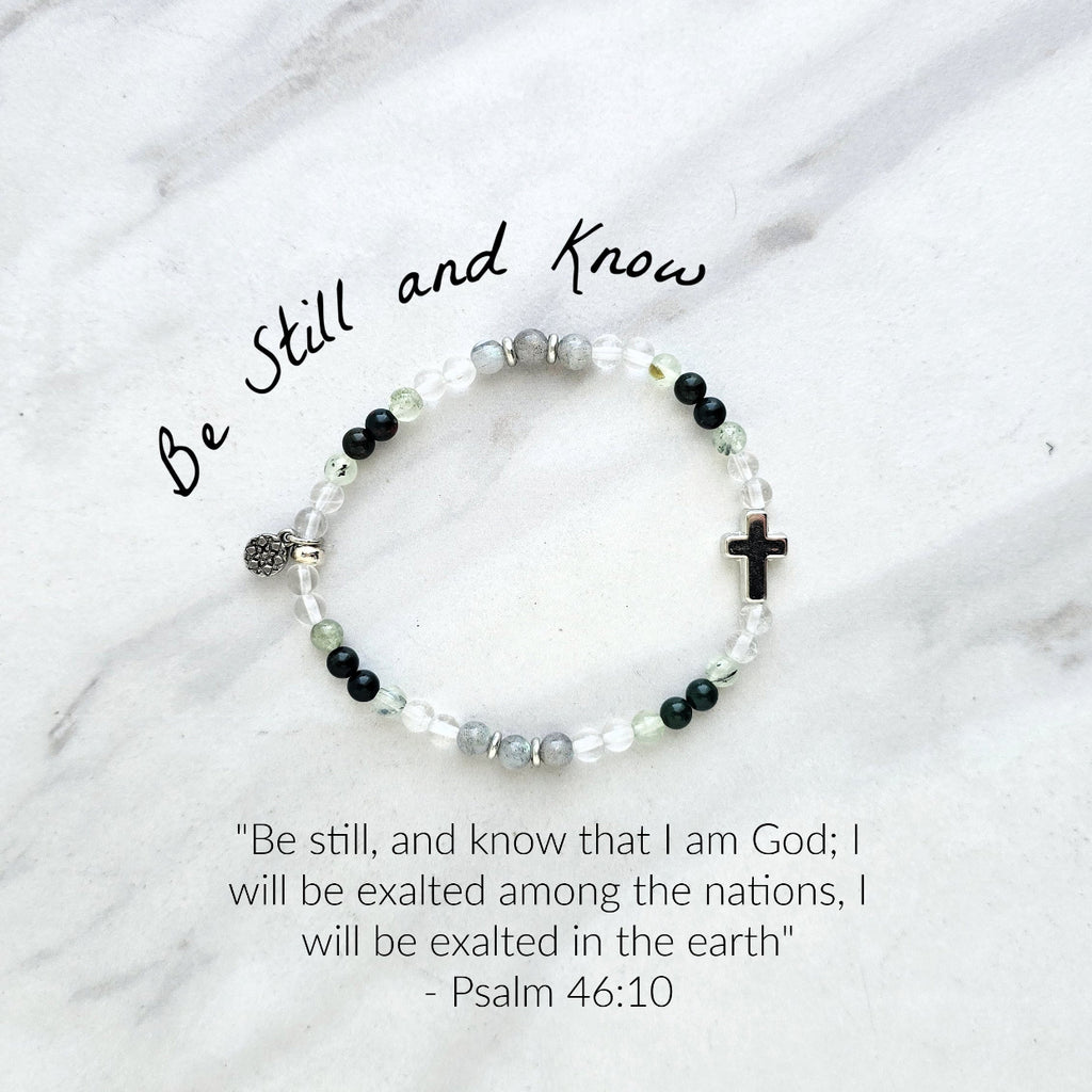 Christian Bracelet with beads and  silver colored cross on a marble background with Psalm 46:10 Be still and know