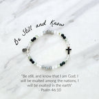 Christian Bracelet with beads and  silver colored cross on a marble background with Psalm 46:10 Be still and know