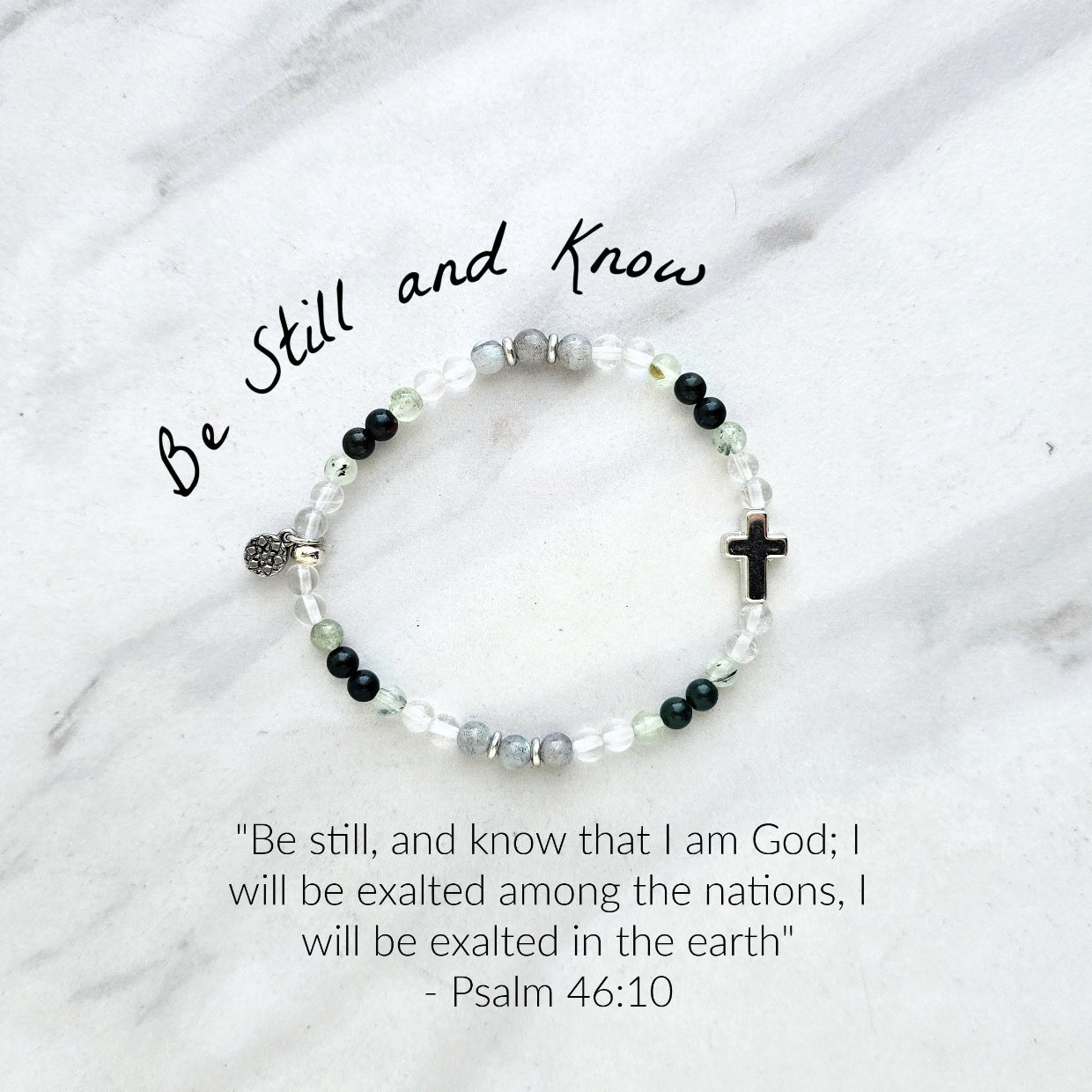 Christian Bracelet with beads and  silver colored cross on a marble background with Psalm 46:10 Be still and know