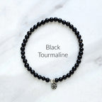 Black tourmaline beaded bracelet on a white marble background