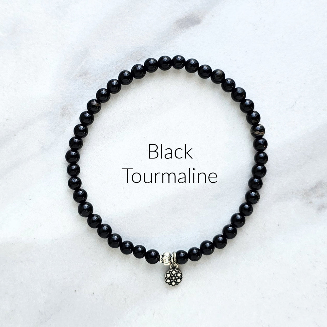 Black tourmaline beaded bracelet on a white marble background