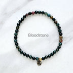Beaded bracelet with a bloodstone charm on a white background