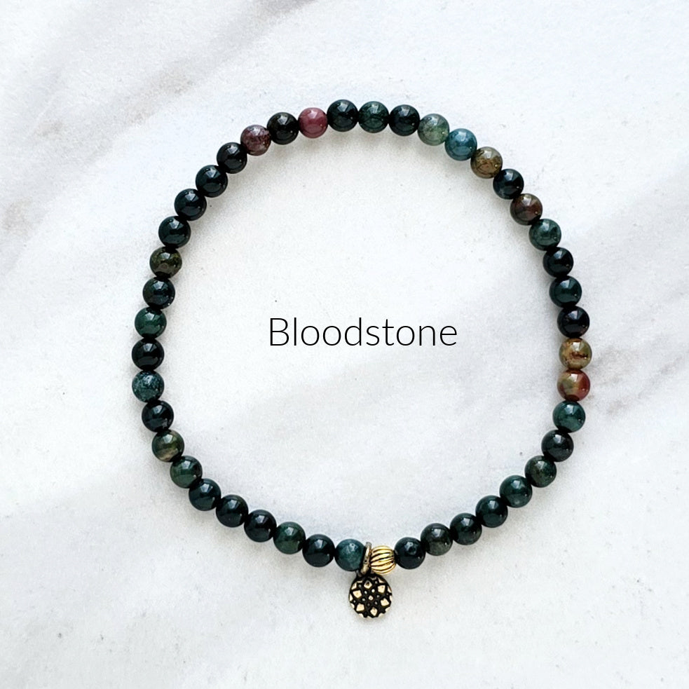Beaded bracelet with a bloodstone charm on a white background