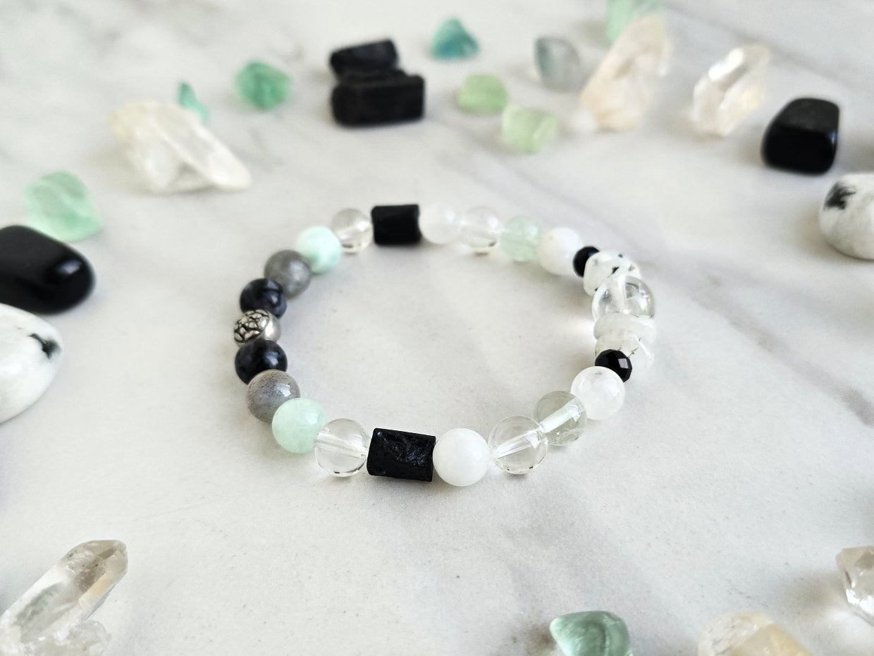 Bracelet with crystals on a marble surface, featuring 'Moxie Monthly' branding. all of both protection crystal bracelet intuition