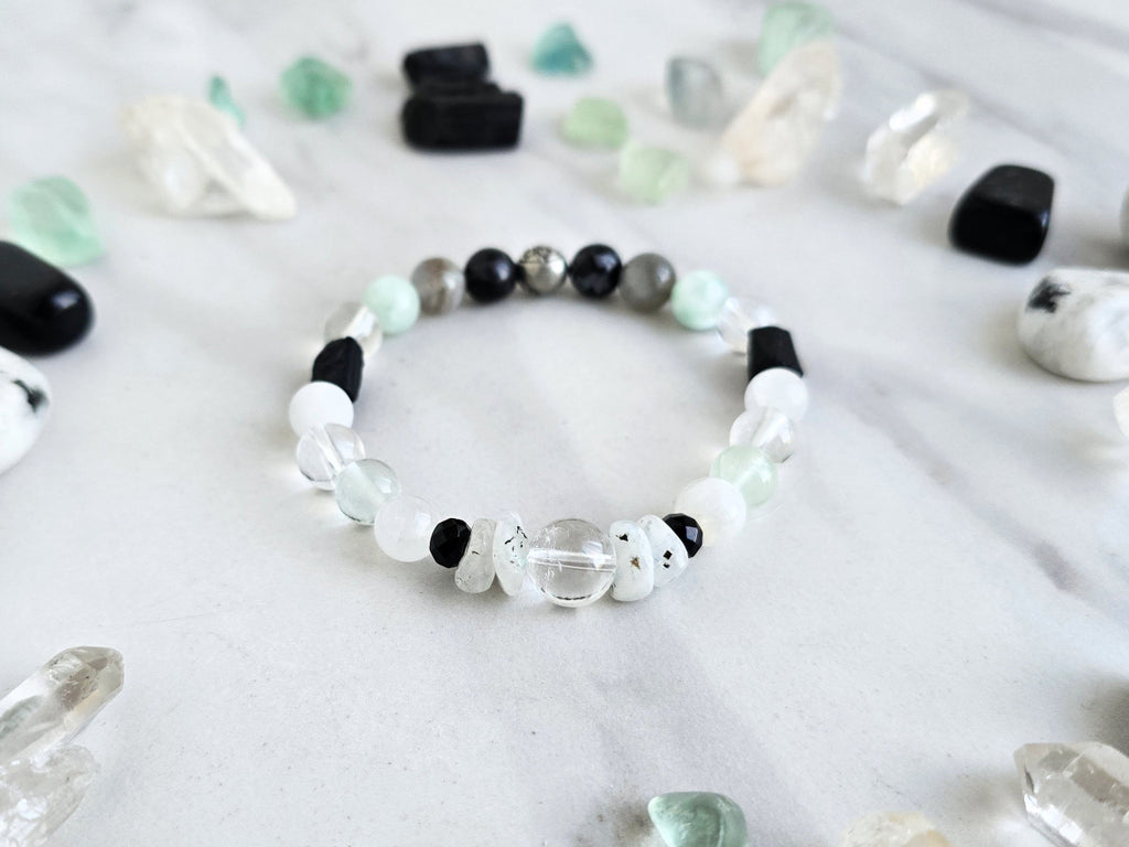 Bracelet with crystals on a marble surface, featuring 'Moxie Monthly' branding. all of both protection crystal bracelet intuition