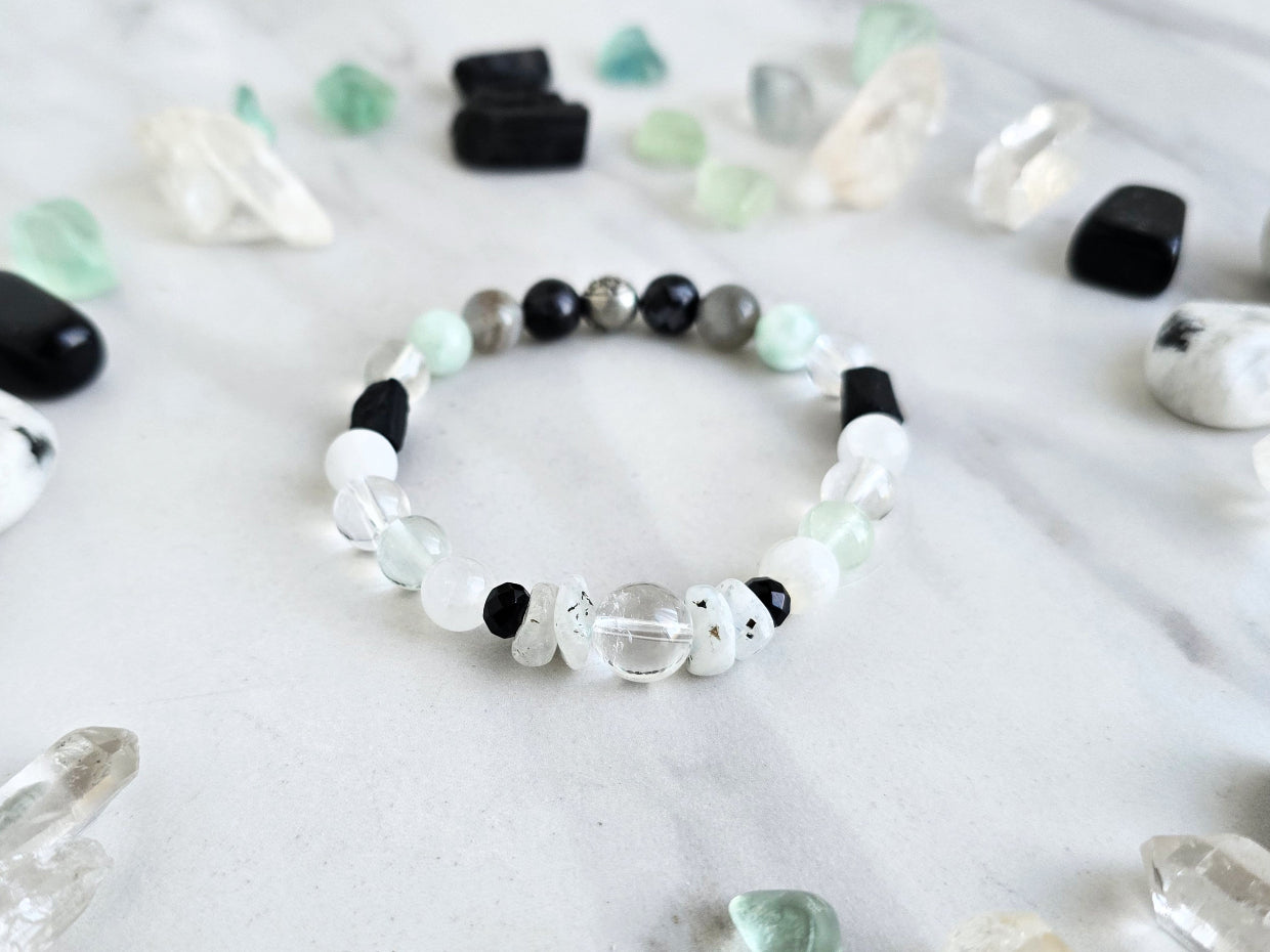 Bracelet with crystals on a marble surface, featuring 'Moxie Monthly' branding. all of both protection crystal bracelet intuition
