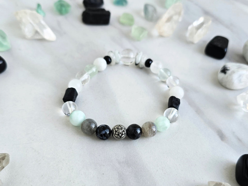 Bracelet with crystals on a marble surface, featuring 'Moxie Monthly' branding. all of both protection crystal bracelet intuition