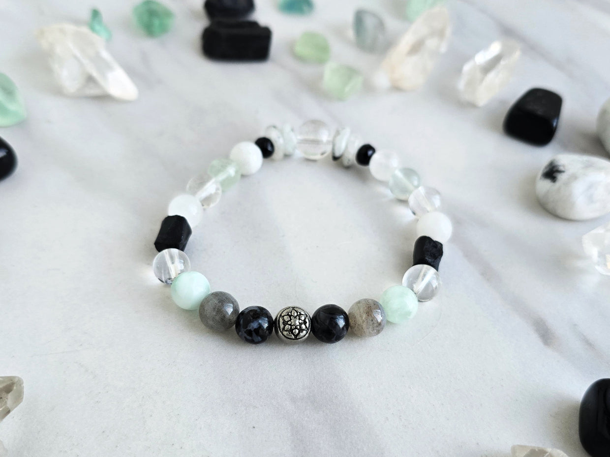 Bracelet with crystals on a marble surface, featuring 'Moxie Monthly' branding. all of both protection crystal bracelet intuition