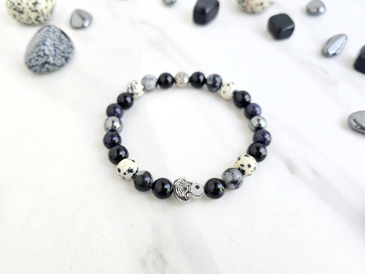 Beaded bracelet surrounded by decorative stones on a white background with 'Duck or Dare' text and brand names. Skelie duck for project fear dakota laden chelsea tanner alex