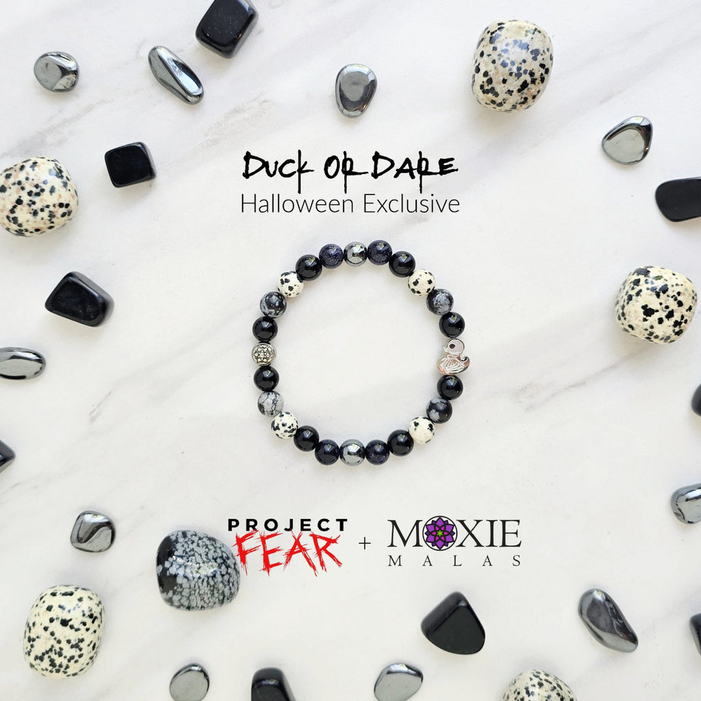 Beaded bracelet surrounded by decorative stones on a white background with 'Duck or Dare' text and brand names. Skelie duck for project fear dakota laden chelsea tanner alex