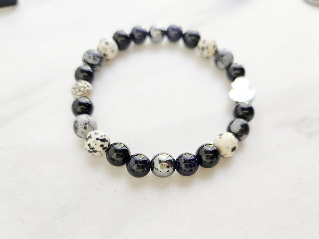 Beaded bracelet surrounded by decorative stones on a white background with 'Duck or Dare' text and brand names. Skelie duck for project fear dakota laden chelsea tanner alex