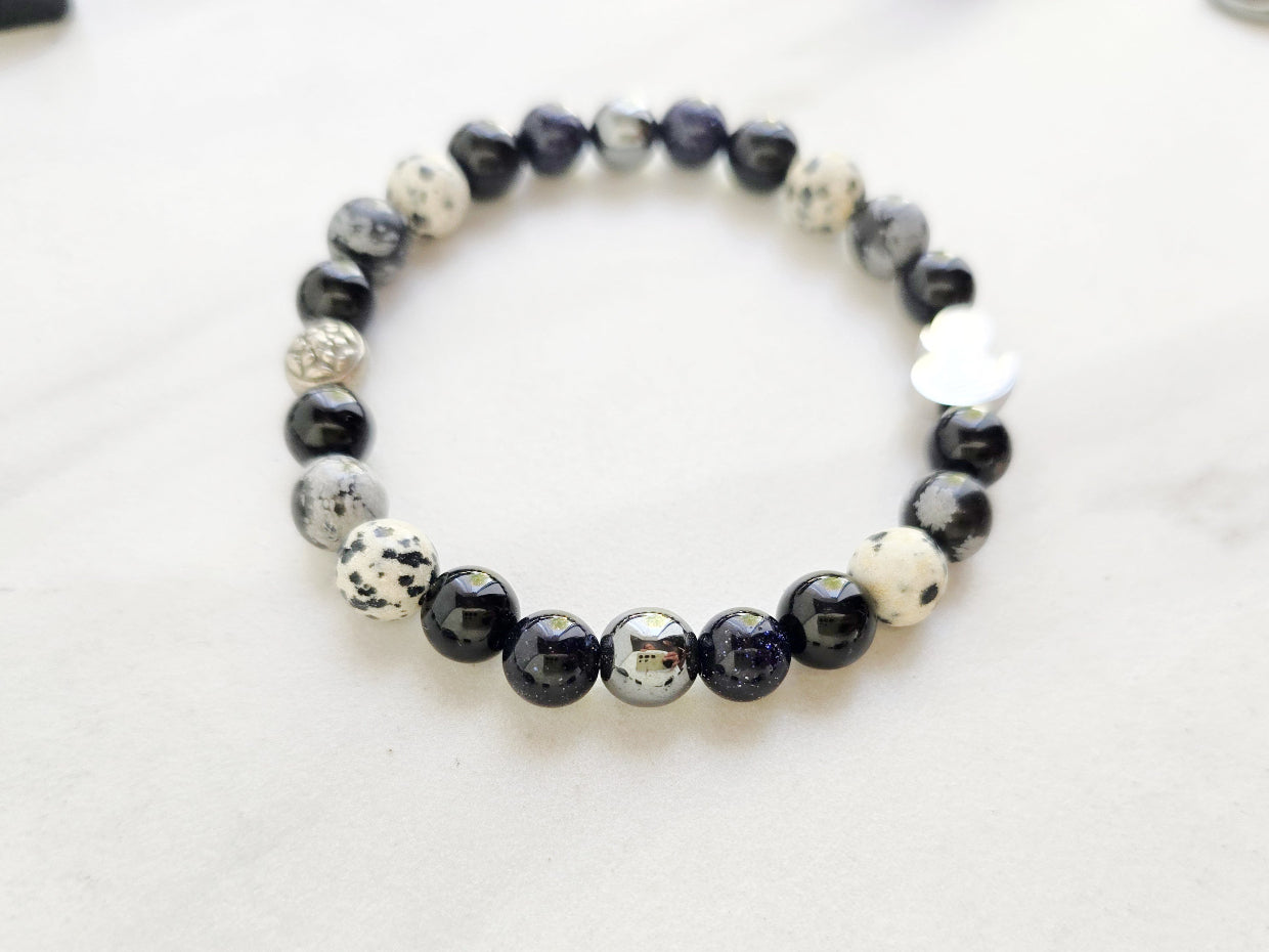 Beaded bracelet surrounded by decorative stones on a white background with 'Duck or Dare' text and brand names. Skelie duck for project fear dakota laden chelsea tanner alex