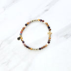 Christian Beaded bracelet with golden cross charm on a white background, featuring a quote from Matthew 6:34. stress and anxiety relief