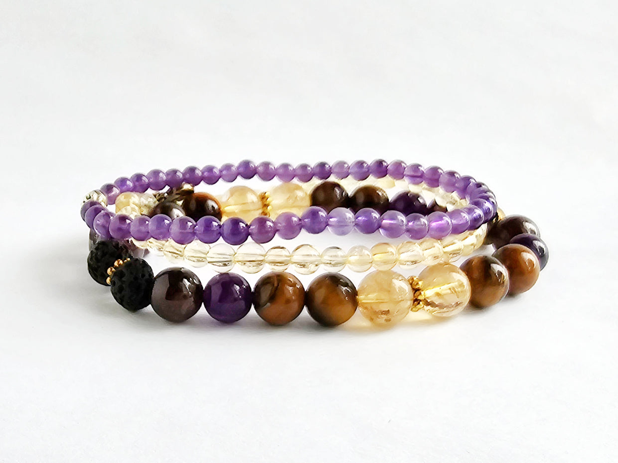 Set of three beaded bracelets with purple, brown, and yellow beads on a white background