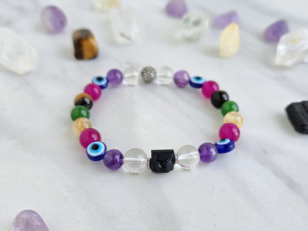 Colorful beaded bracelet on a white surface with crystals and text about collaboration between Ghost Sister and Moxie Malas.