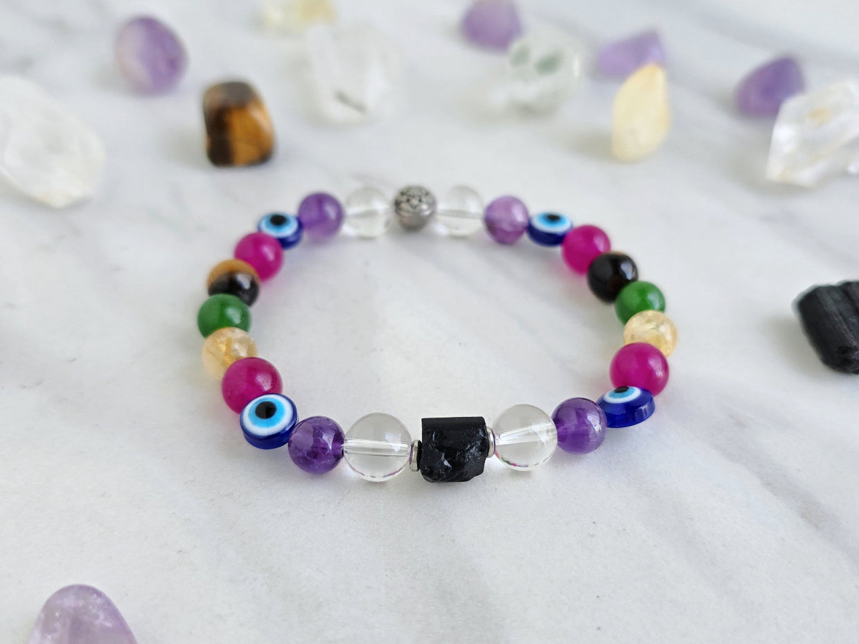 Colorful beaded bracelet on a white surface with crystals and text about collaboration between Ghost Sister and Moxie Malas.