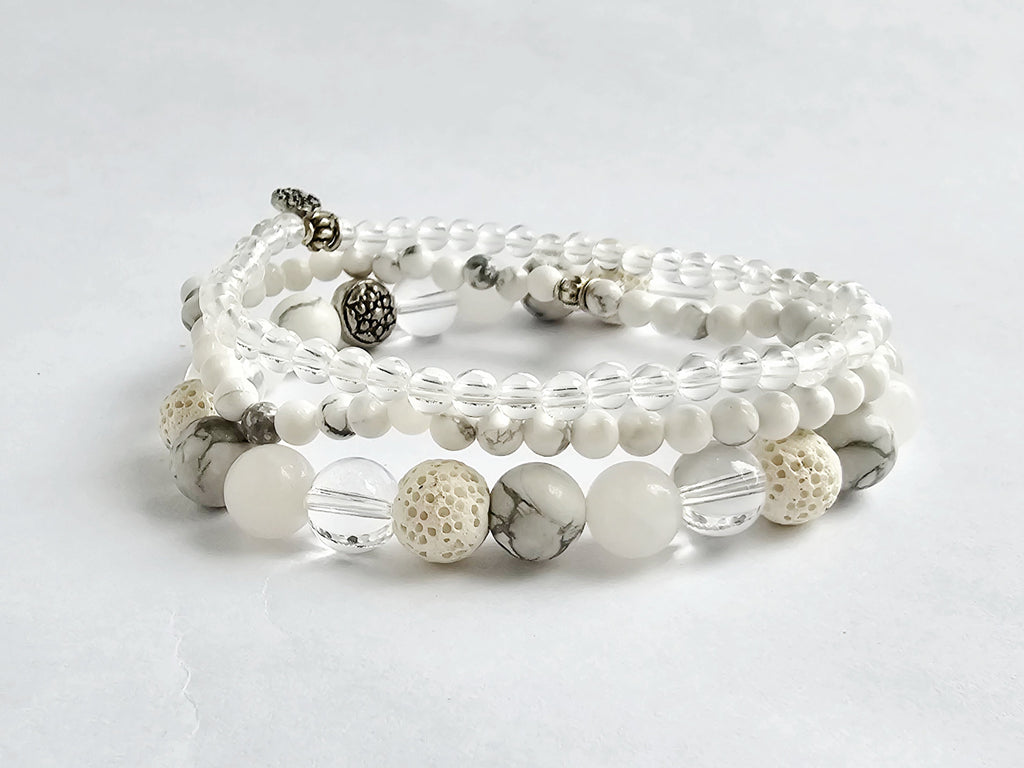 Set of white and gray beaded bracelets on a light gray background