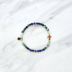 Beaded bracelet with a golden cross on a white marble background, featuring a quote from Proverbs 20:5. Christian Bracelet