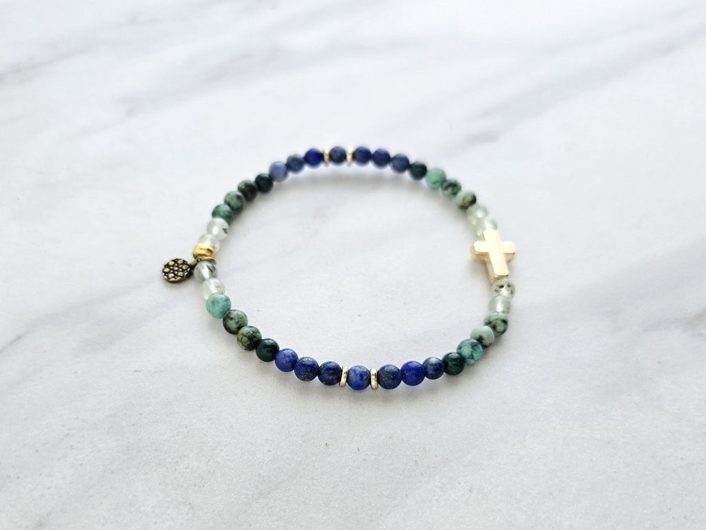 Beaded bracelet with a golden cross on a white marble background, featuring a quote from Proverbs 20:5. Christian Bracelet