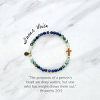 Beaded bracelet with a golden cross on a white marble background, featuring a quote from Proverbs 20:5. Christian Bracelet