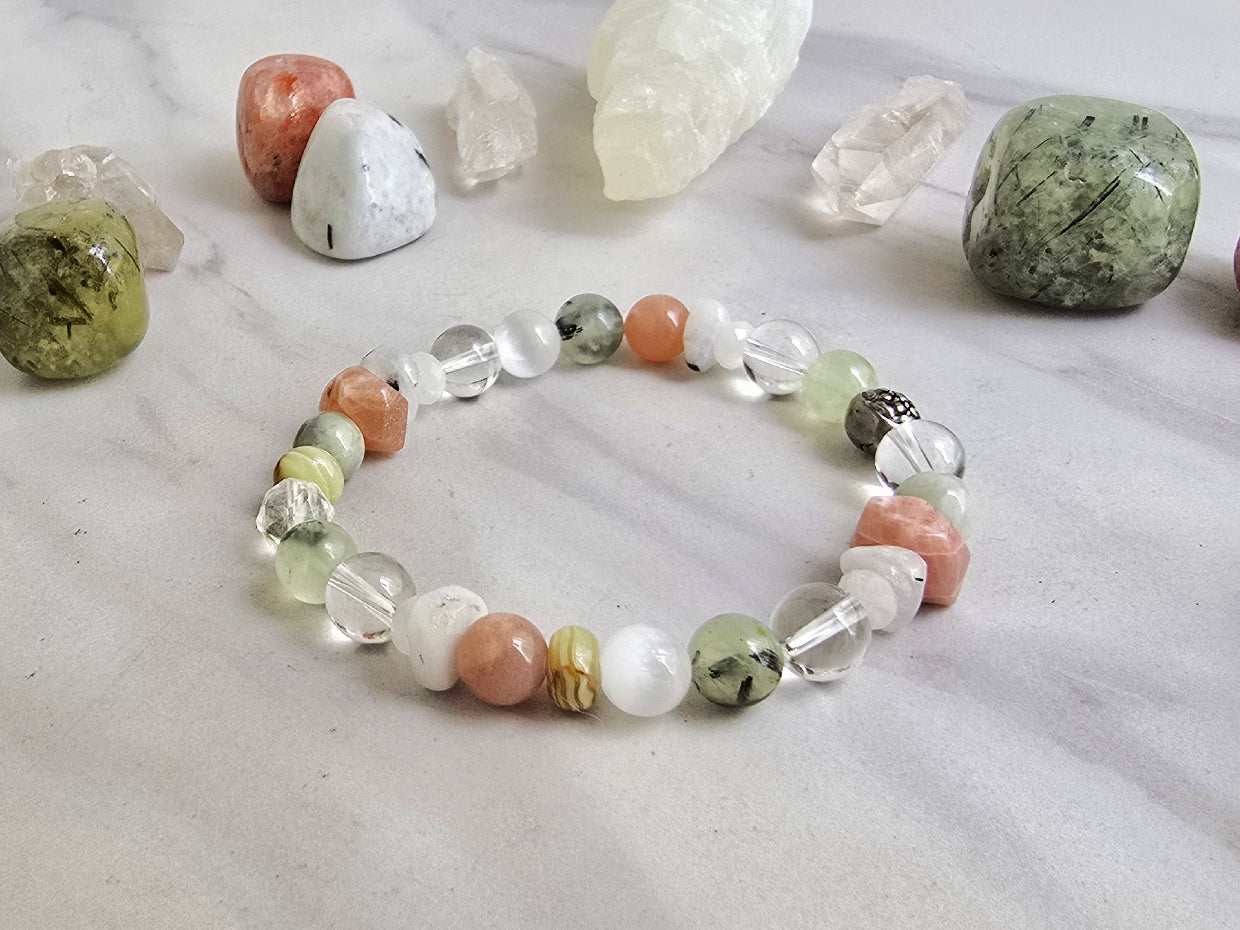 Crystal bracelet with stones on a marble surface, featuring 'Moxie Monthly' branding. June 2026 the calling