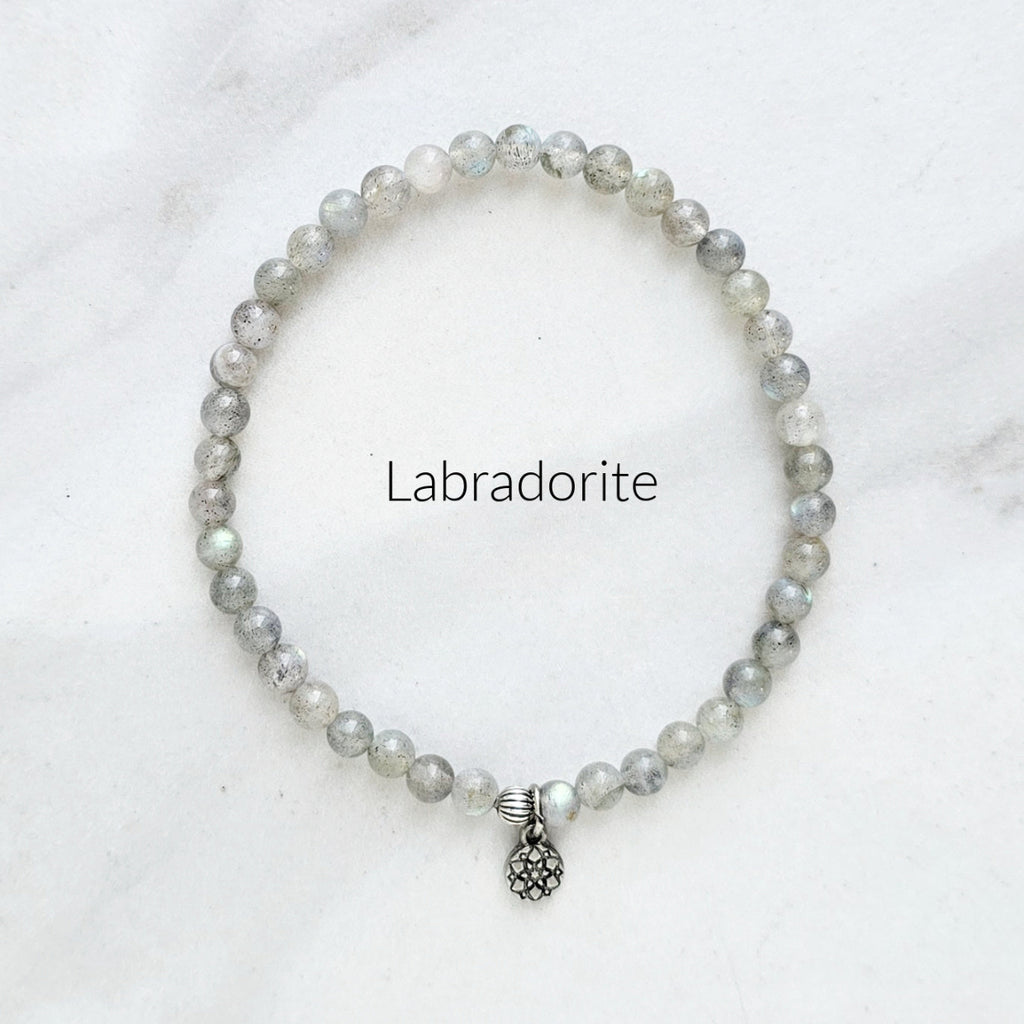 Labradorite bracelet with a silver charm on a white background