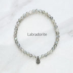 Labradorite bracelet with a silver charm on a white background