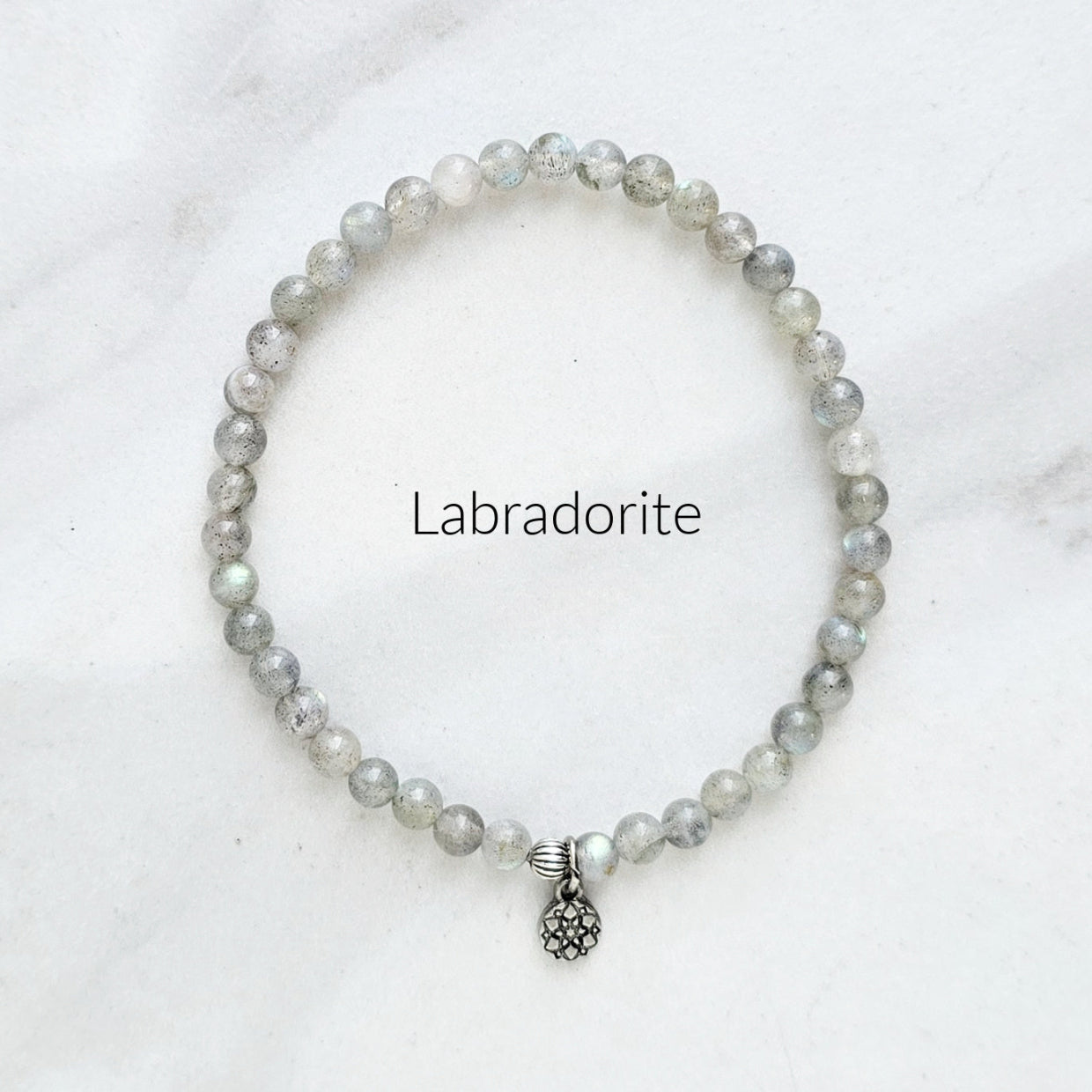 Labradorite bracelet with a silver charm on a white background