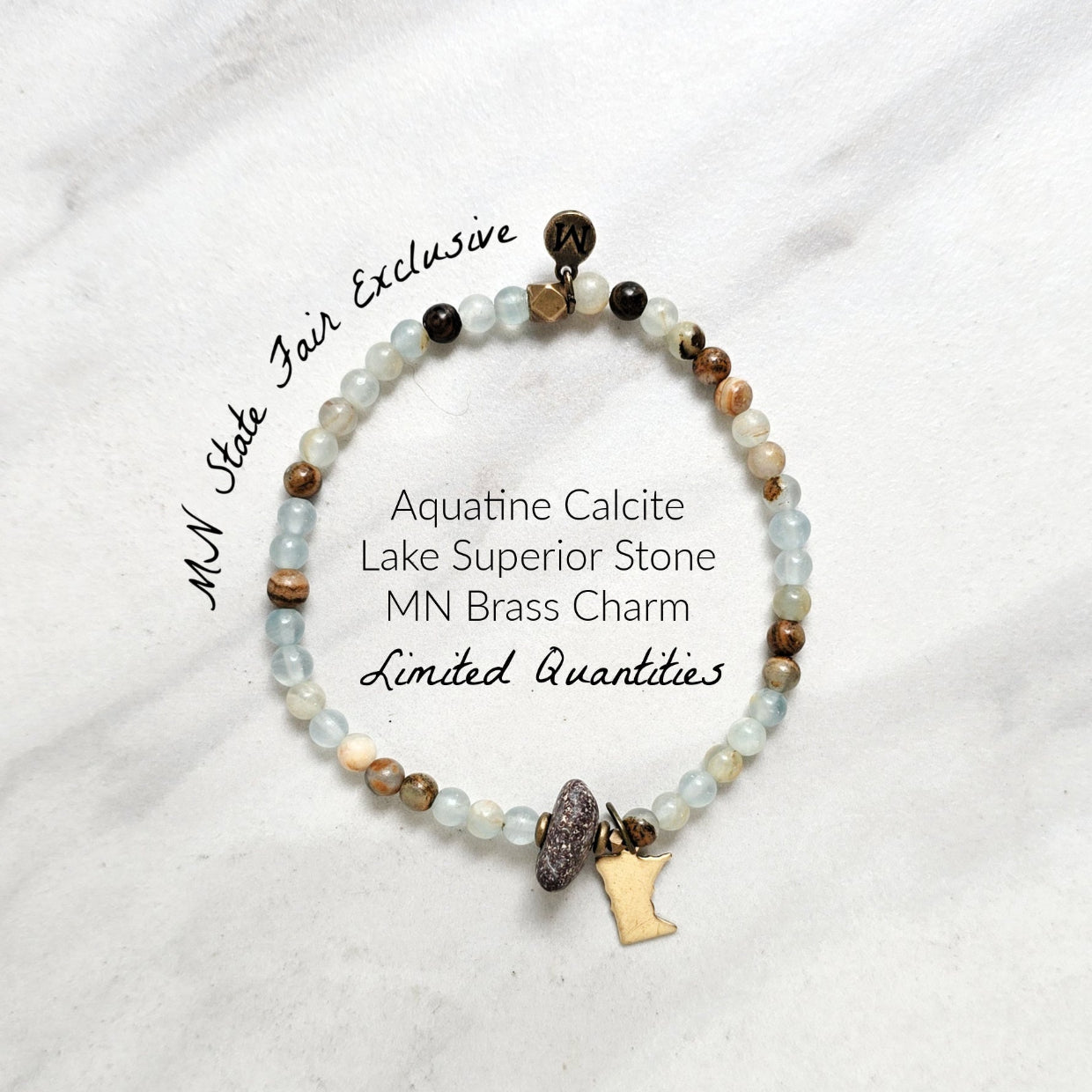 A beaded stretch bracelet featuring light blue-green aquatine calcite beads, brown and cream accent beads, a dark brown bead with a white inlay, a small gold-toned charm, and a gold-toned Minnesota state silhouette charm, displayed on a white marble background with text overlays. MN State Fair Exclusive Moxie Malas
