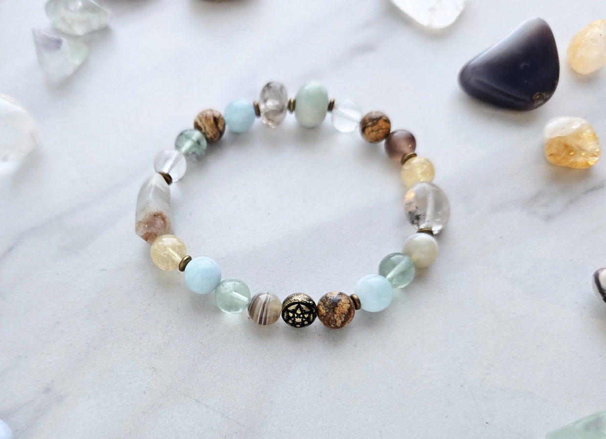 Bracelet with stones on a marble surface, featuring 'Moxie Monthly' march 2026 courage to begin again bracelet club 