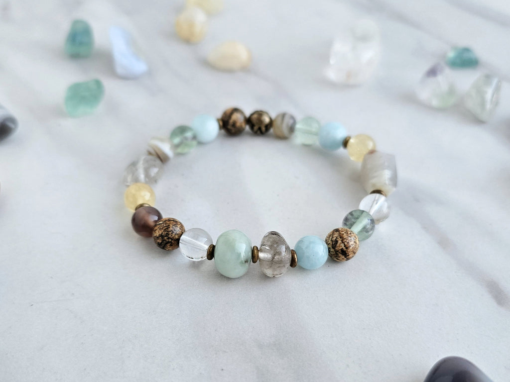 Bracelet with stones on a marble surface, featuring 'Moxie Monthly' march 2026 courage to begin again bracelet club 