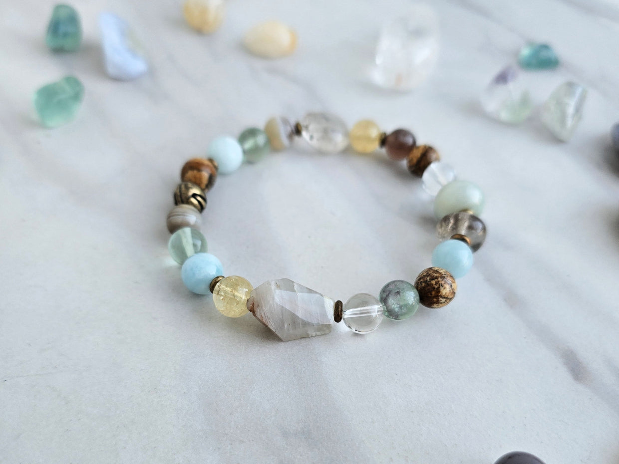 Bracelet with stones on a marble surface, featuring 'Moxie Monthly' march 2026 courage to begin again bracelet club 
