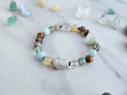 Bracelet with stones on a marble surface, featuring 'Moxie Monthly' march 2026 courage to begin again bracelet club 