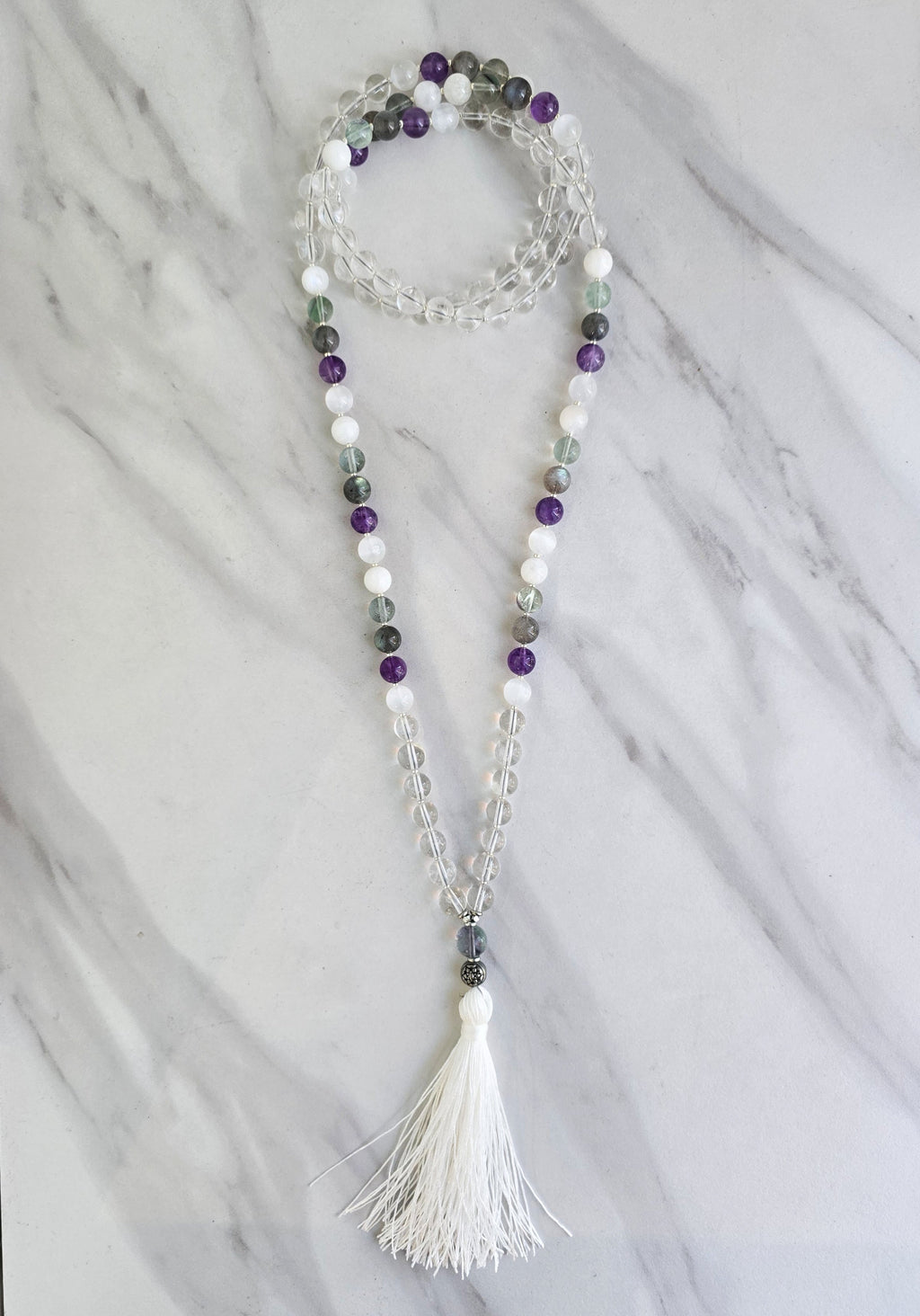 Beaded necklace with a tassel on a marble surface metatron meditation beads mala