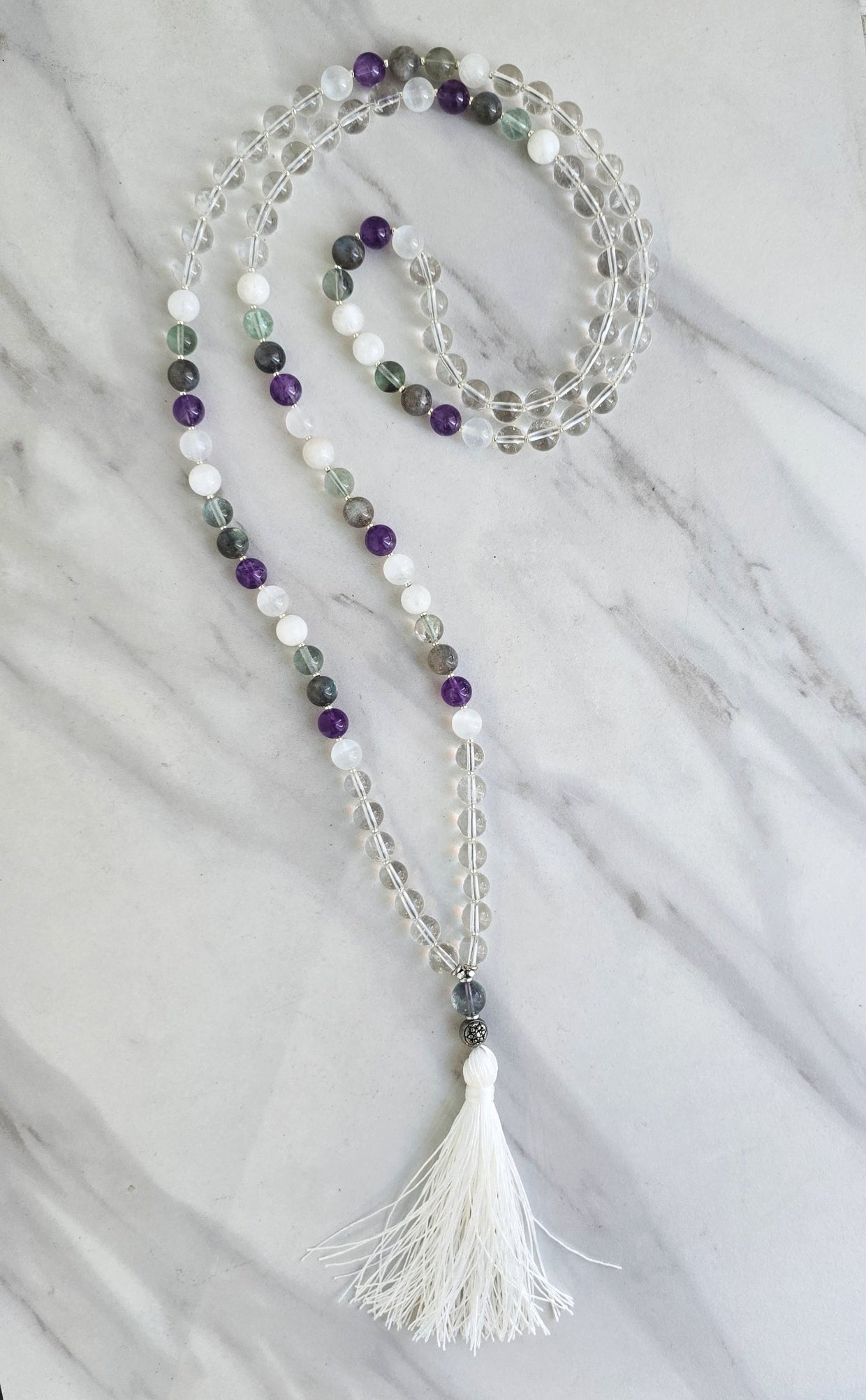 Beaded necklace with a tassel on a marble surface metatron meditation beads mala