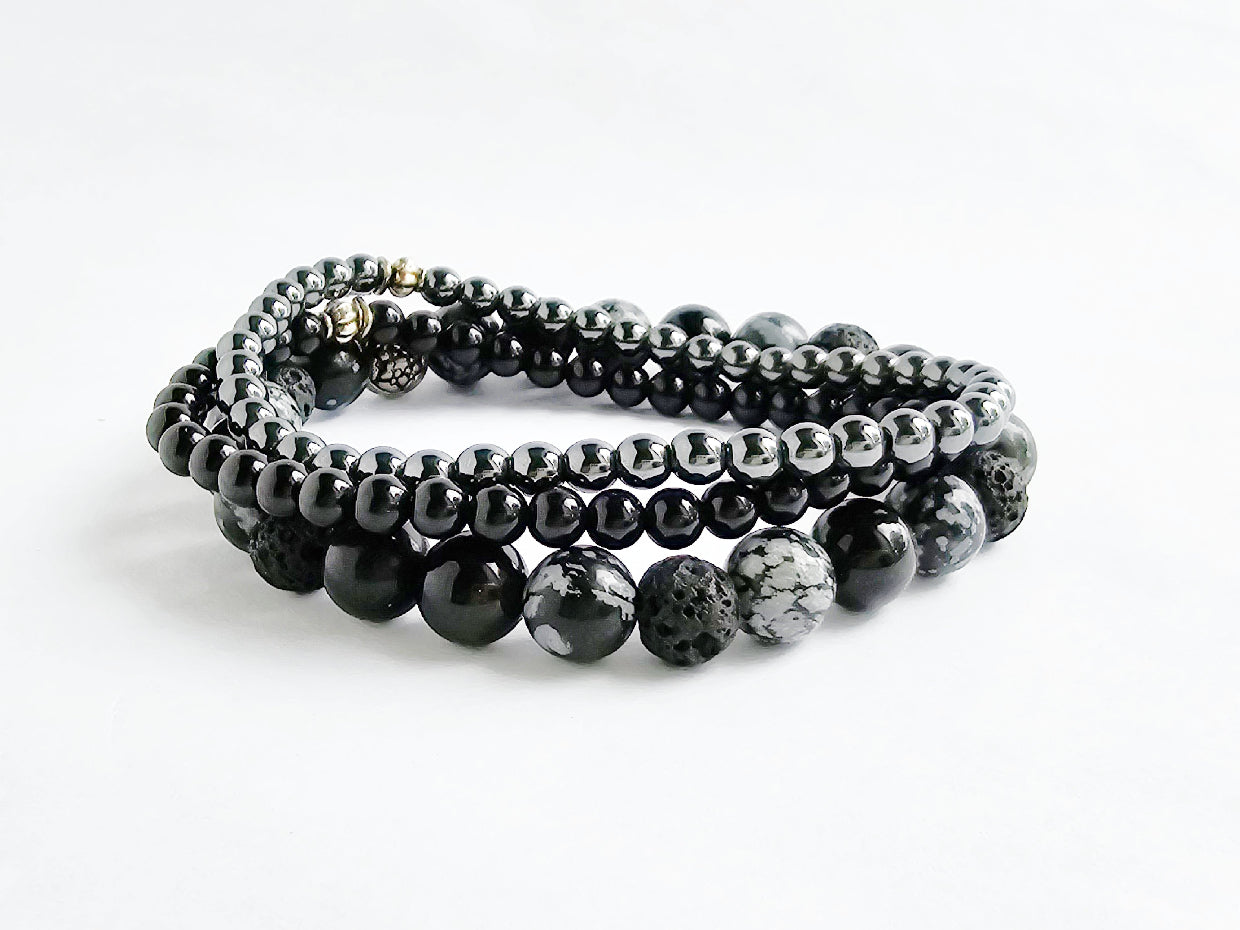 Set of black beaded bracelets on a white background