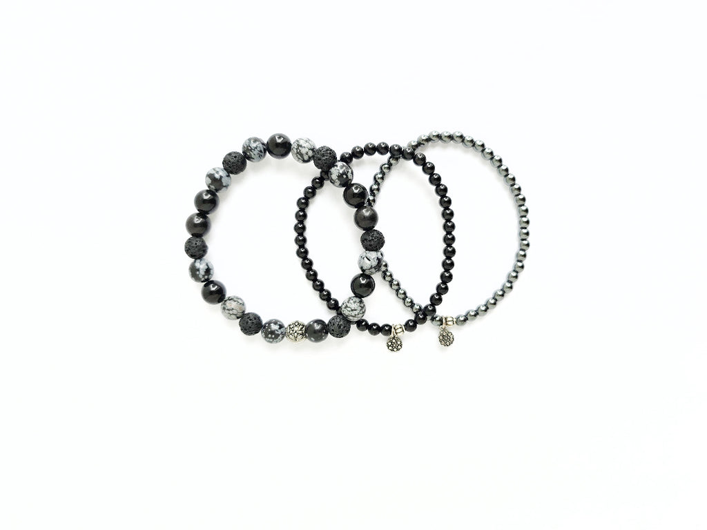Three black beaded bracelets on a white background