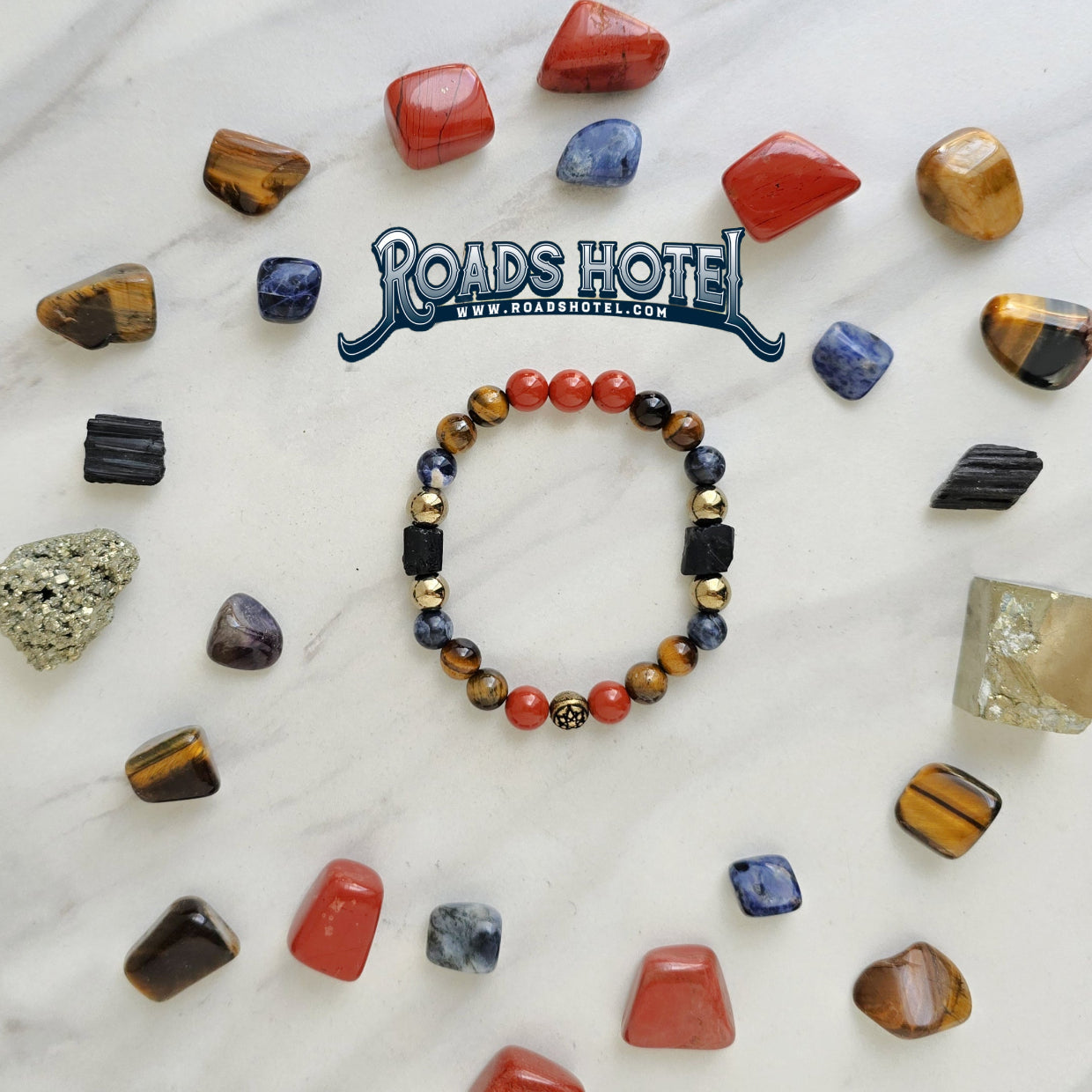 Colorful beaded bracelet on a marble surface with various stones and 'Roads Hotel' branding.