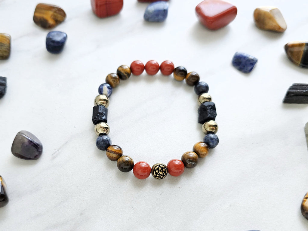 Colorful beaded bracelet on a marble surface with various stones and 'Roads Hotel' branding.
