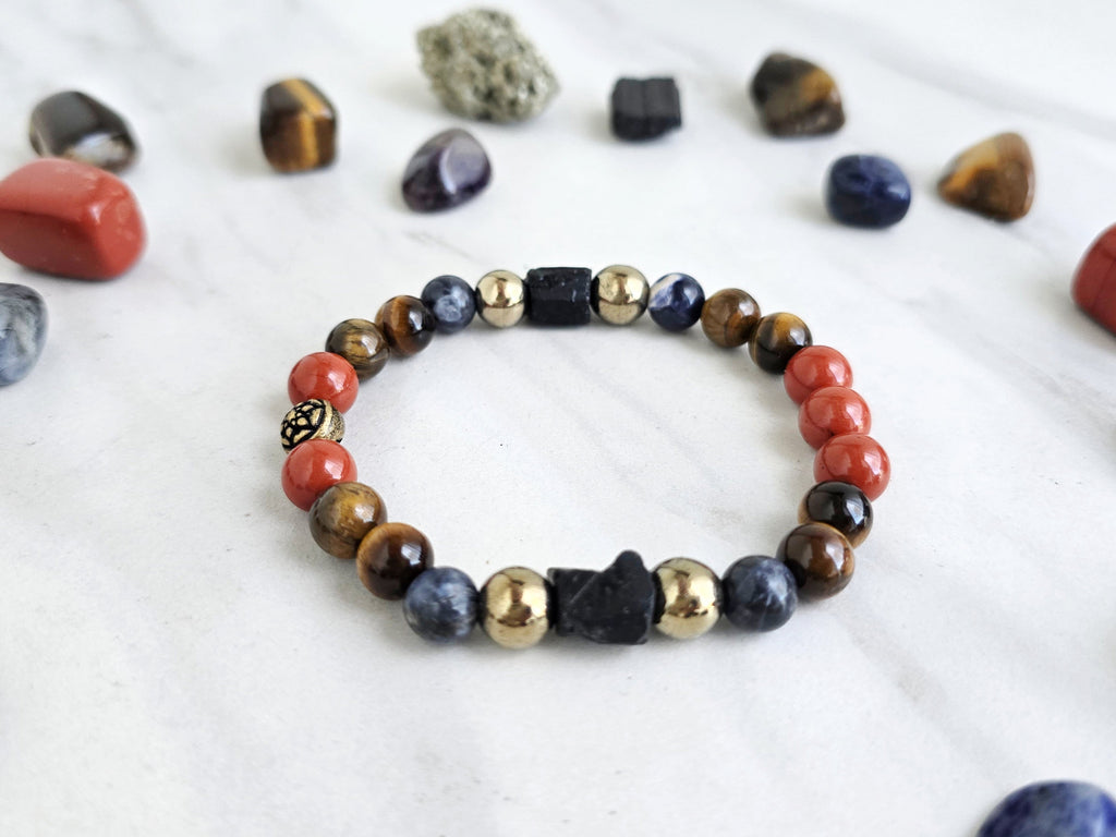 Colorful beaded bracelet on a marble surface with various stones and 'Roads Hotel' branding.