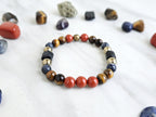 Colorful beaded bracelet on a marble surface with various stones and 'Roads Hotel' branding.