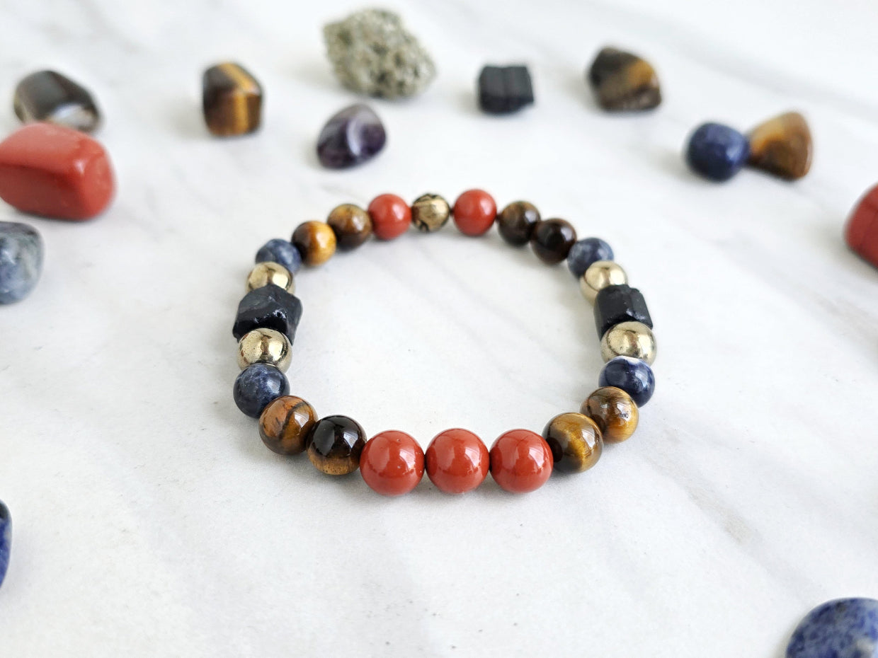 Colorful beaded bracelet on a marble surface with various stones and 'Roads Hotel' branding.