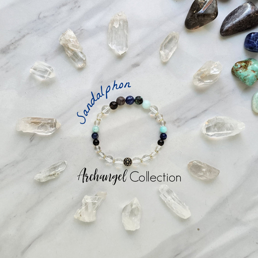 Bracelet with beads on a marble surface surrounded by crystal stones, featuring 'Sandalphon' and 'Archangel Collection'.