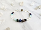Bracelet with beads on a marble surface surrounded by crystal stones, featuring 'Sandalphon' and 'Archangel Collection'.